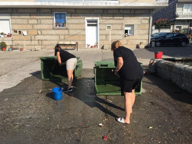 Dúas veciñas de Lucenza limpan os colectores de lixo da localidade.